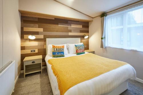 Barmby on the MoorにあるFoxglove Lodge with Hot Tubの黄色い毛布が掛けられた大きなベッドのある寝室