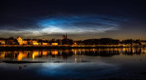 a city skyline at night with a body of water at Central Old Town Apartments - Green Loft and BelleView in Toruń