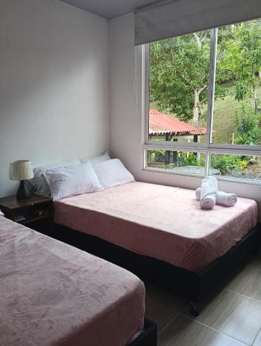 two beds in a bedroom with a window at Encantador refugio enclavado en las montañas in Guadual