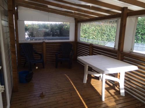 a screened in porch with a white table and two chairs at MOBIL HOME tout confort in Talmont