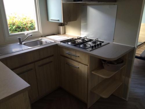 a kitchen with a stove and a sink and a window at MOBIL HOME tout confort in Talmont