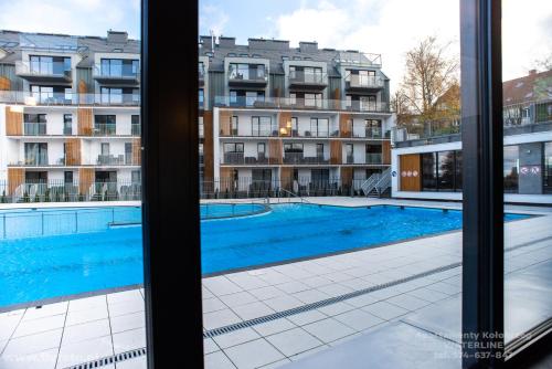 Elle offre une vue sur la piscine depuis sa fenêtre. dans l'établissement Waterline Apartments Deluxe Class, Family Place Kołobrzeg, à Kołobrzeg