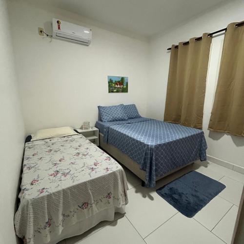a bedroom with two beds and a air conditioner at Recanto do Sossego in Porto Seguro