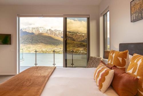 a bedroom with a large bed with a large window at Bel Lago - every room with a lake view in Queenstown
