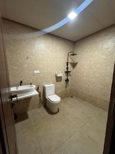 a bathroom with a toilet and a sink and a light at PereraTree in Ja-Ela