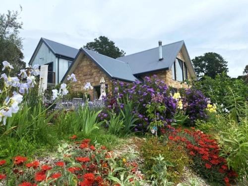 ein Steinhaus mit Blumen davor in der Unterkunft The FatPonyLodge in Hepburn Springs