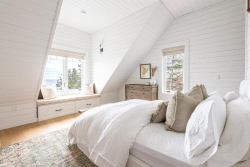 a white bedroom with a bed and two windows at Atlantic Pearl - Luxurious Ocean Front Experience 