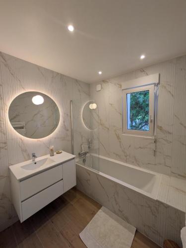 a white bathroom with a tub and a sink and a bath tubermott at La p'tite marquise in Roscoff