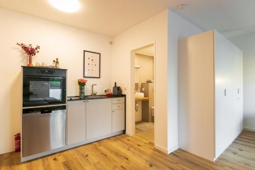 eine Küche mit weißen Schränken und einem Flachbildfernseher in der Unterkunft Oldtown in Trier