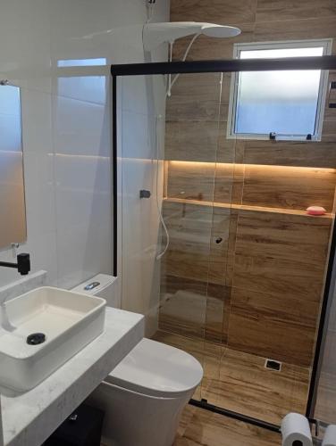 ein Badezimmer mit Toilette, Waschbecken und Dusche in der Unterkunft Recanto Amora in Boicucanga