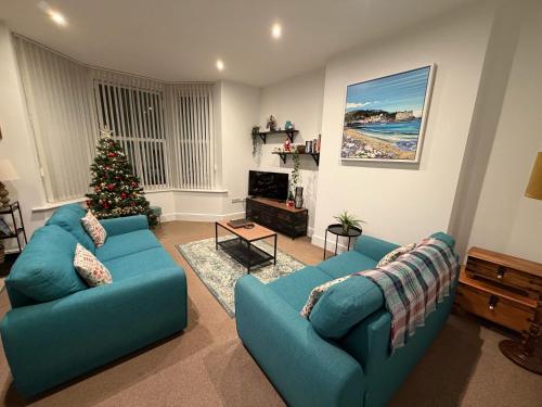 スランディドノにあるPrivate Parking, Central Llandudno, King Bed with Ensuite at Clement Lodgeのリビングルーム(青いソファ2台、クリスマスツリー付)