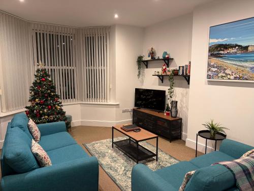 スランディドノにあるPrivate Parking, Central Llandudno, King Bed with Ensuite at Clement Lodgeのリビングルーム(クリスマスツリー、青いソファ付)