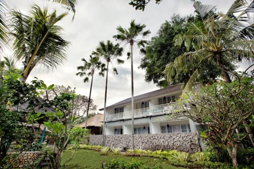 um edifício branco com palmeiras ao fundo em Segara Village Hotel em Sanur