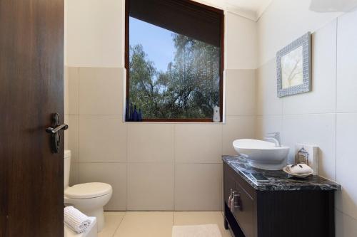 a bathroom with a toilet and a sink and a window at Watermill Studios in Gordonʼs Bay