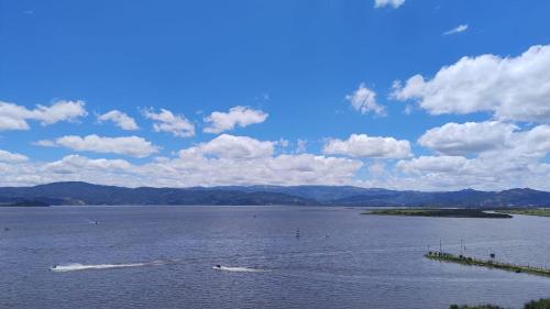 a large body of water with mountains in the background at La Gruta Glamping in Fúquene