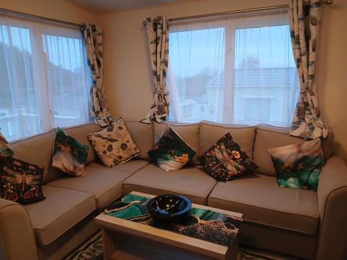 a living room with a couch with pillows at Warm and Cosy, Torbay Waterside Holiday Home in Paignton