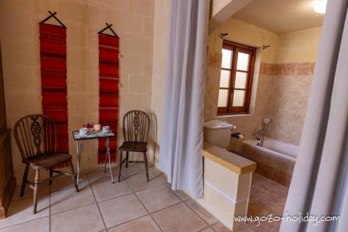 een badkamer met 2 stoelen, een tafel en een bad bij Tal Lilly Xaghra in Xagħra