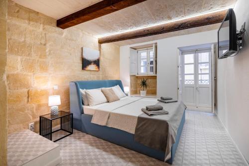 a bedroom with a blue bed and a window at The Glen Residences in Senglea