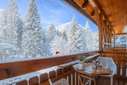 a balcony with a table and chairs and snow covered trees at Alpine Retreat Gaja Kranjska Gora - Happy Rentals in Kranjska Gora