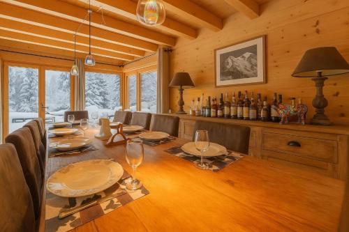 un comedor con una mesa con sillas y botellas de vino en Alpine Luxury Chalet Pool & Jacuzzi, en Cordon