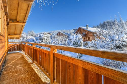 Una terraza de madera con árboles cubiertos de nieve y una casa. en Alpine Luxury Chalet Pool & Jacuzzi, en Cordon