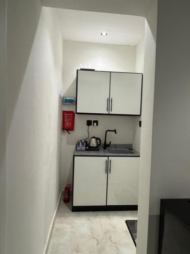 a small kitchen with white cabinets and a sink at Luxury studio with smart self check-in أستديو راقي بدخْول ذاتي حي الصحافة in Riyadh