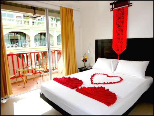a bedroom with a bed with two red decorations on it at Boomerang Inn in Patong Beach