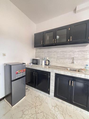a kitchen with black cabinets and a stainless steel refrigerator at Immeuble Sali Laye in Darou Rhamane