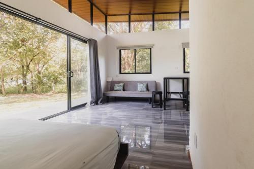 Un dormitorio con una cama y un sofá en una habitación. en Newly built Surf Hideaway in Avellanas Beach, en Playa Avellana