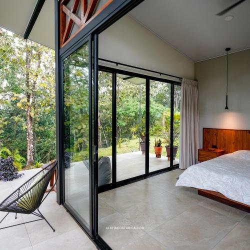 ein Schlafzimmer mit Glastüren, einem Bett und einem Stuhl in der Unterkunft Vacation Home Retreat, 3BD, 3BA, Sleeps 8 in Delicias