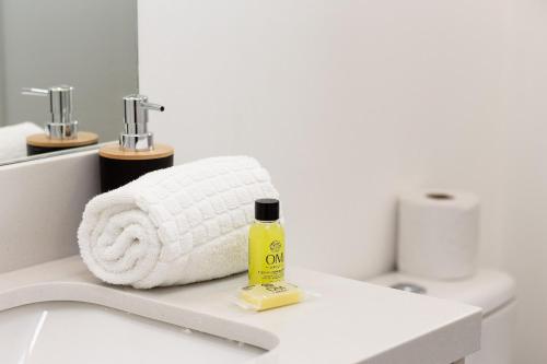 a white bathroom with a towel and a bottle of soap at Studios Sampa - Vila Buarque - Santa Casa in São Paulo