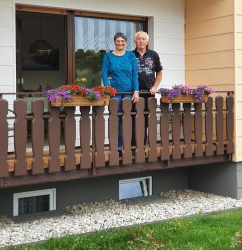 a man and woman standing on a balcony with flowers at Naturblick in Berndorf