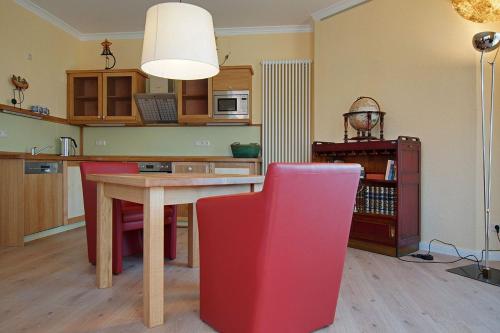 cocina con mesa y silla roja en Ferienhaus Seegang Mit Eingezäuntem Grundstück, en Flessenow