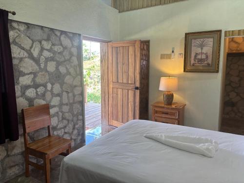 ein Schlafzimmer mit einem Bett, einem Stuhl und einer Tür in der Unterkunft The Ridge - Stone Cottage in Buff Bay