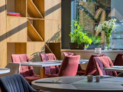 クラクフにあるノボテル クラクフ セントラムのテーブルと椅子と窓のあるレストラン