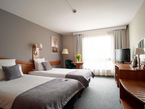 een hotelkamer met twee bedden en een televisie bij Mercure Cieszyn in Cieszyn