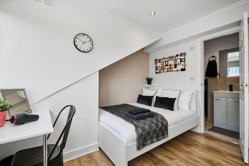 a bedroom with a bed and a desk and a clock at Beechwood Terrace Studios in Leeds