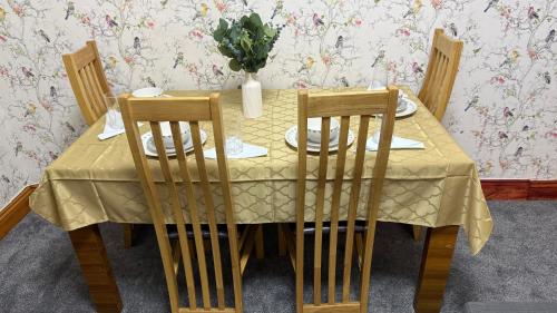 a yellow table with chairs and a vase of flowers on it at Pat Signature Stays in Kingsthorpe