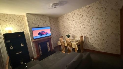 a living room with a television and a table with chairs at Pat Signature Stays in Kingsthorpe