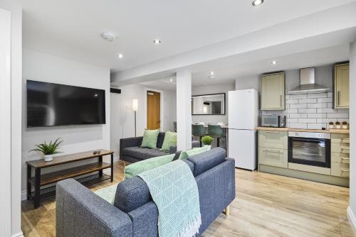 a living room with two blue couches and a kitchen at Stylish Headingley Apartments in Leeds
