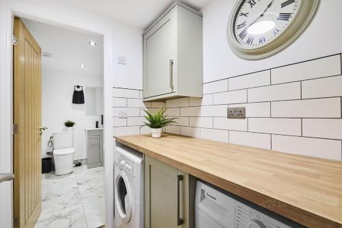 a kitchen with a washing machine and a clock on the wall at Stylish Headingley Apartments in Leeds