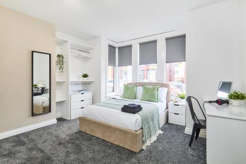 a white bedroom with a bed and a desk at Stylish Headingley Apartments in Leeds