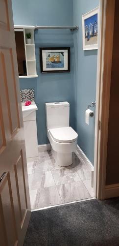 a bathroom with a white toilet and blue walls at Grange House Budget Rooms in Leeds