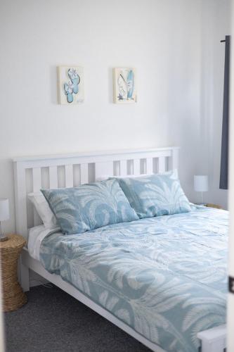 a bed with a blue comforter and two pictures on the wall at Bombo Beach House in Kiama