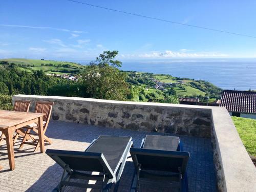 a patio with a table and chairs and the ocean at Casabelavista Iii in Fajã do Araújo