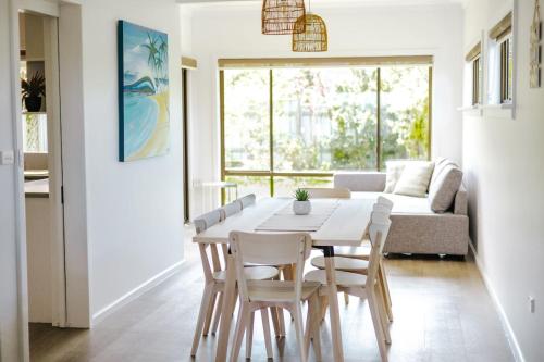 een woonkamer met een witte tafel en stoelen bij Bombo Beach House in Kiama