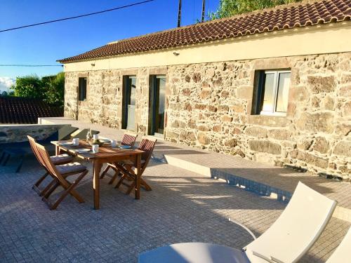 a patio with a table and chairs and a building at Casabelavista Iii in Fajã do Araújo