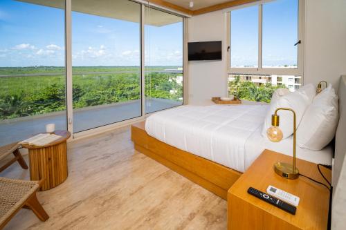une chambre avec un lit et de grandes fenêtres dans l'établissement Greta Puerto Morelos, à Puerto Morelos