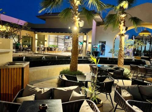 un restaurant avec des tables, des chaises et des palmiers dans l'établissement Aldau heights luxury, à Hurghada