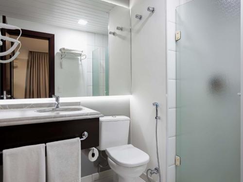 a bathroom with a toilet and a sink and a shower at Mercure Jaragua do Sul in Jaraguá do Sul